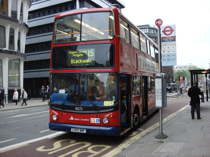 A red double-decker bus at a bus stop in London