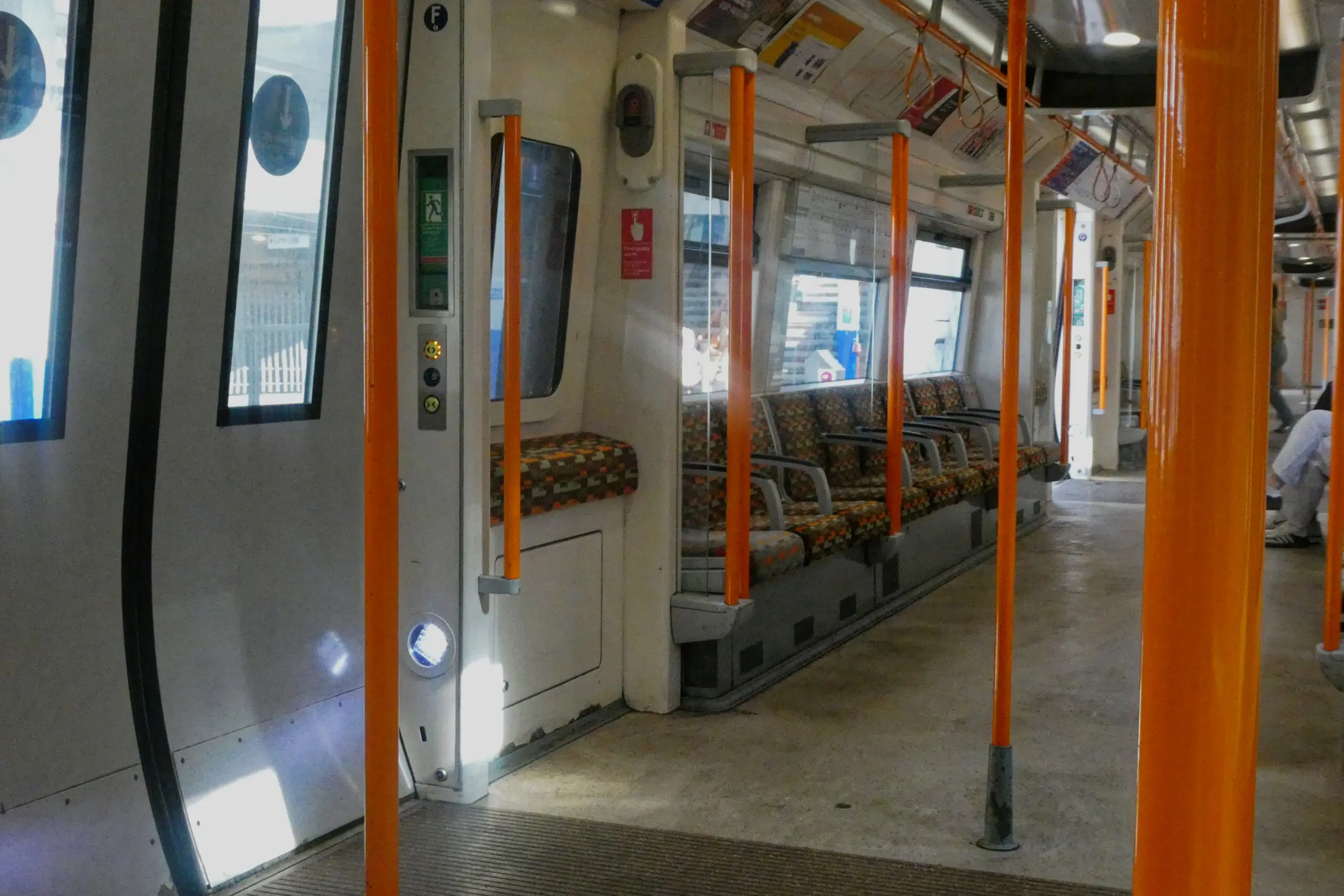 Inside a London Overground train on the Windrush line, showing orange grab poles and patterned seats