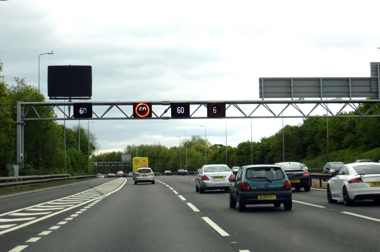 Smart motorway gantry displaying variable speed limits above traffic on a UK motorway
